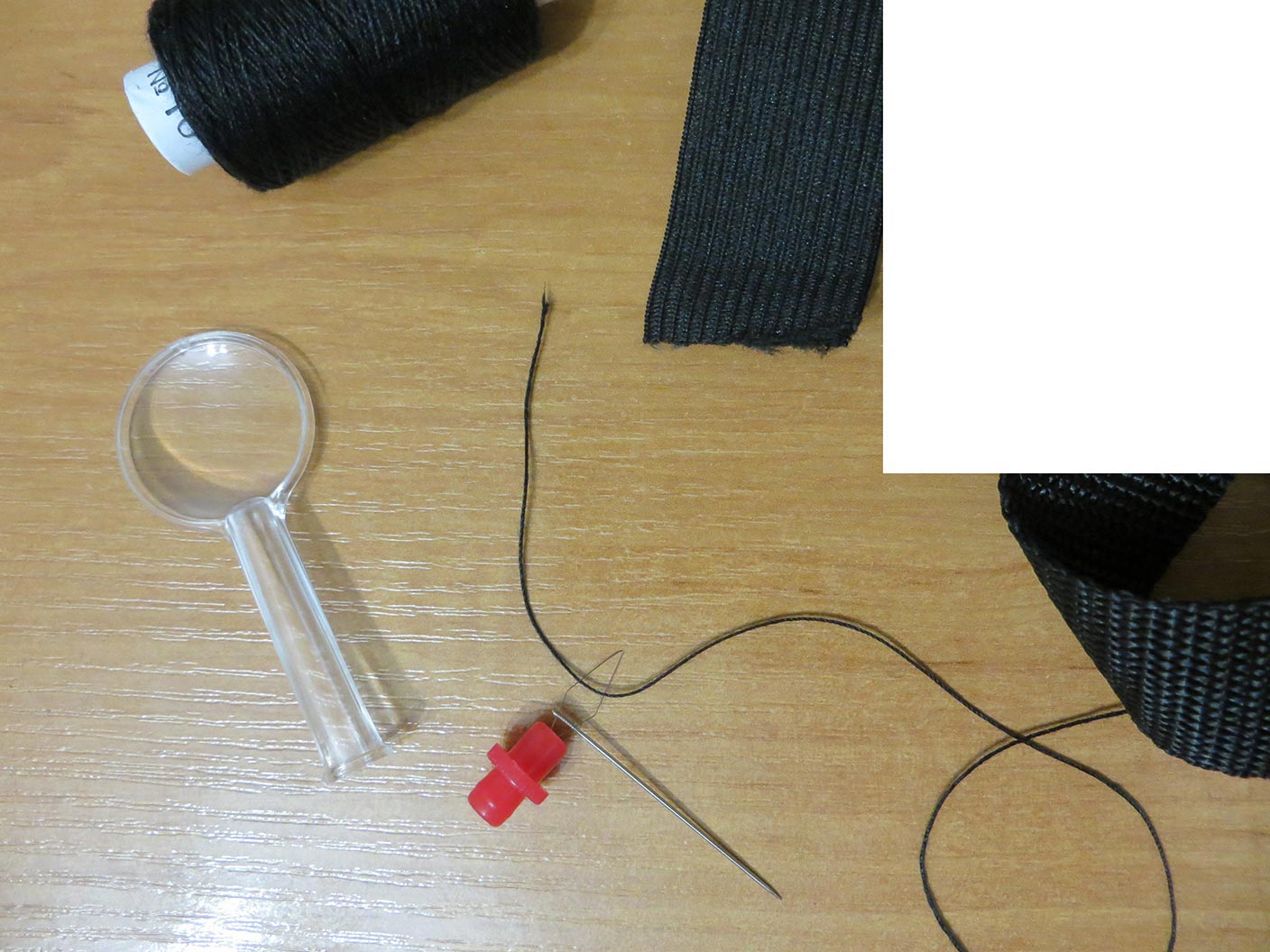 Иголка с приспособлением для лёгкого продевания нитки; нитки № 10; нейлоновая тесьма (справа); швейная эластичная (растягивающаяся) лента (вверху)